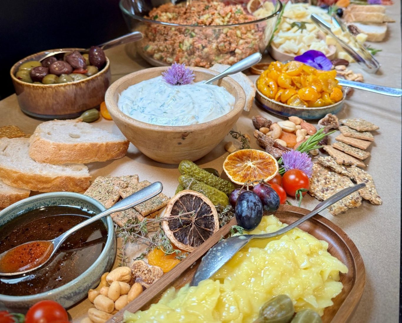 Bunte Auswahl an Gerichten und Snacks auf einem Tisch, darunter Brot, Salate und Dips.