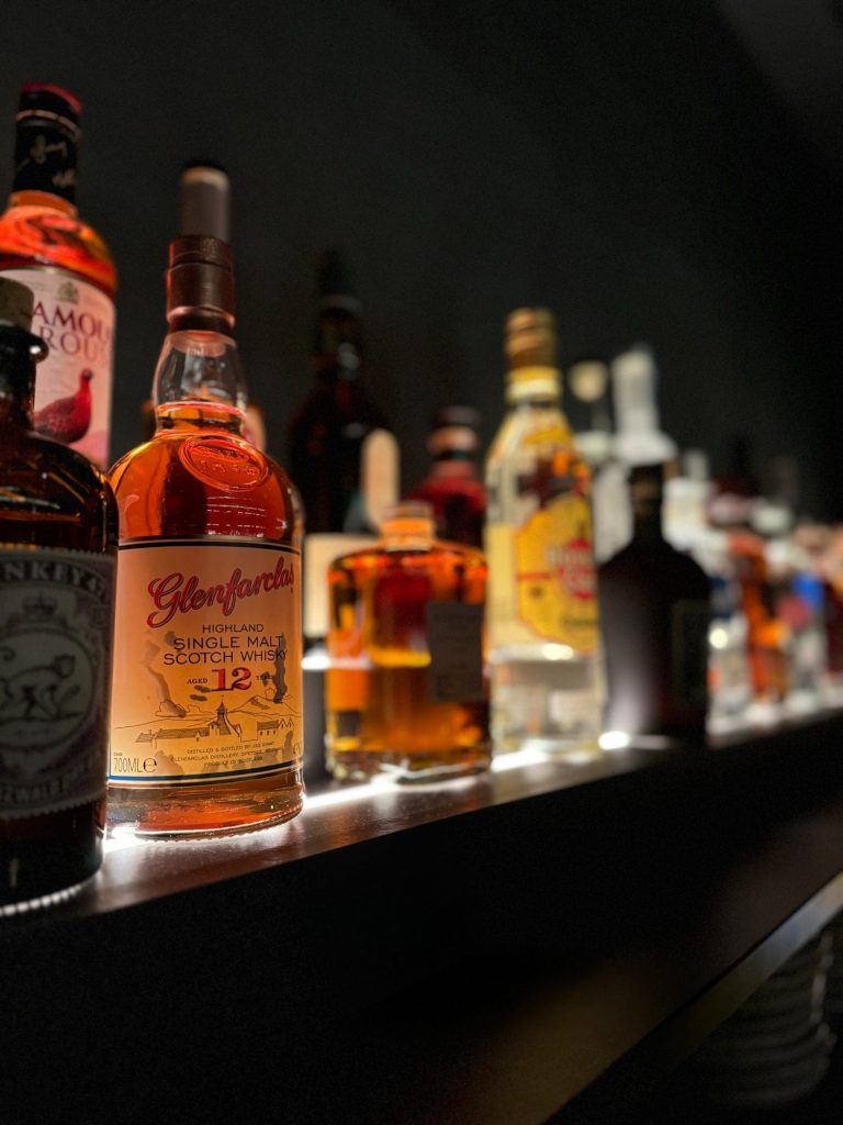 Regalierte Spirituosenflaschen in einer beleuchteten Bar, dunkel Hintergrund.