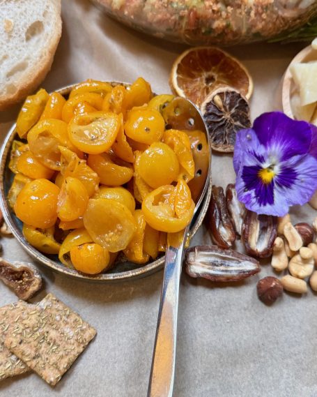 Gelbe Kirschtomaten mit essbaren Blüten, Nüssen und getrockneten Früchten.