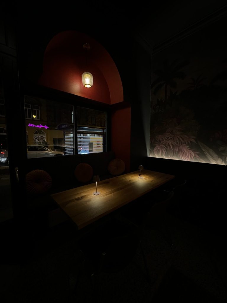 Rote Ecke in der Bar Halbvoll mit einem Tisch und weichem Licht, dekorativen Wänden und Fenstern.