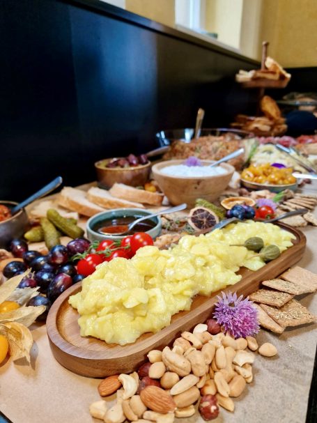 Eine Auswahl an Käse, Oliven, Nüssen, Trauben und Trockenfrüchten auf einem Holzbrett.