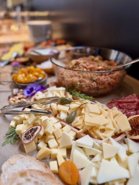 Ein vielseitiges Buffet mit Käse, Wurst, Brot, Dips und frischem Obst.