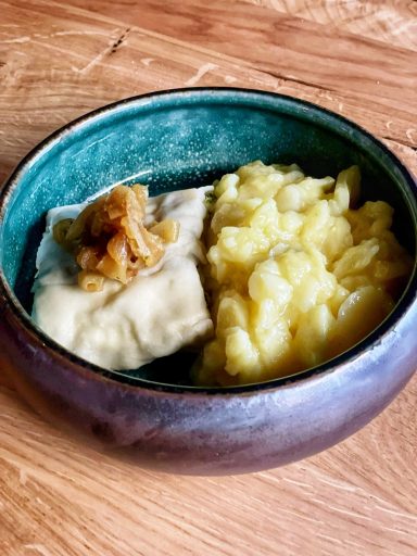 Schüssel mit Kartoffelsalat und einer Maultasche, garniert mit geschmelzten Zwiebeln.