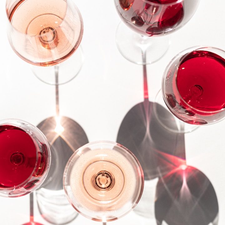 Mehrere Weingläser mit rosafarbenem Wein, auf einem weißen Untergrund.